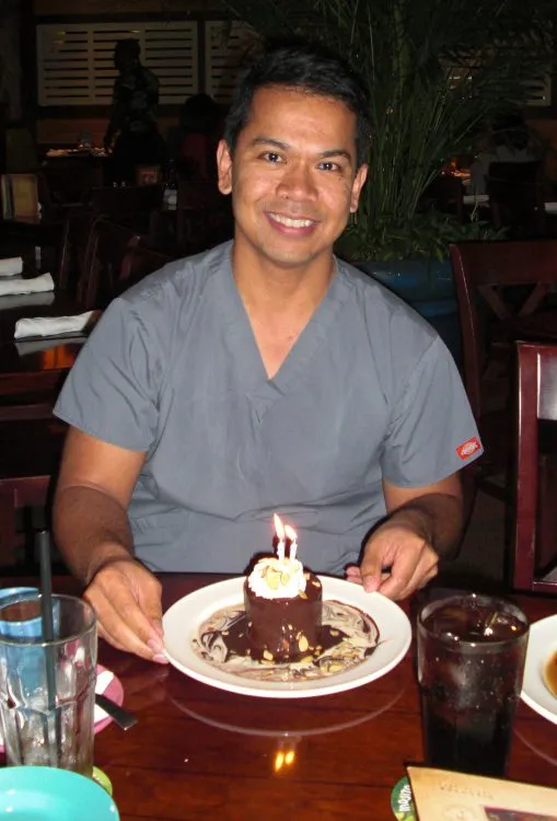 Photo of Dr. Aguila in front of birthday cake