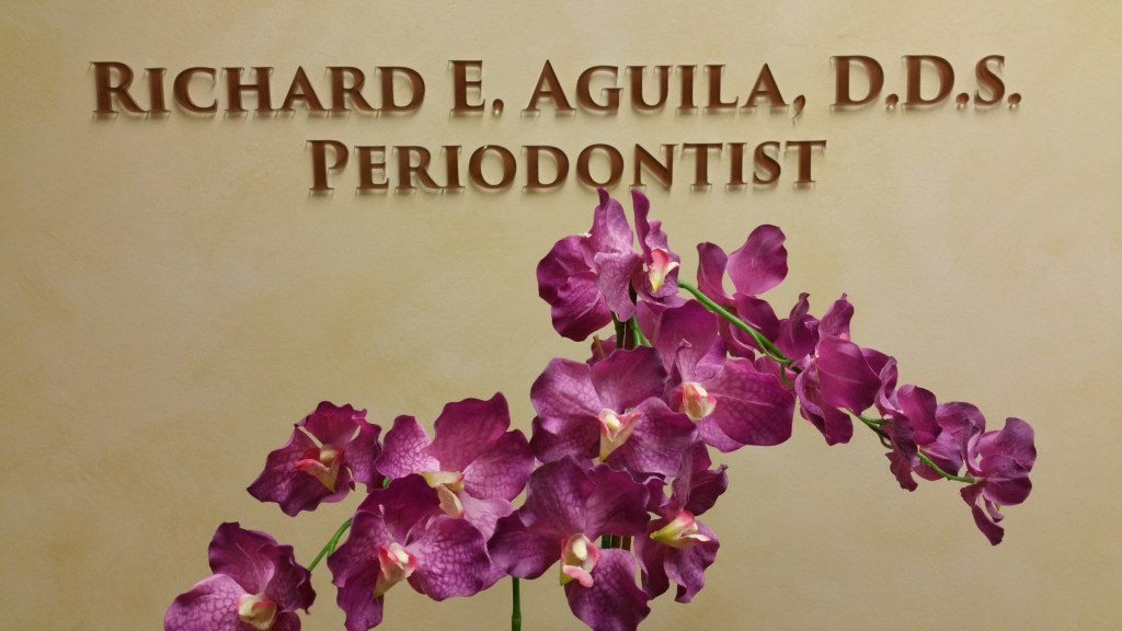 Interior Photo: Practice sign for Richard E. Aguila, DDS, Periodontist behind purple orchids